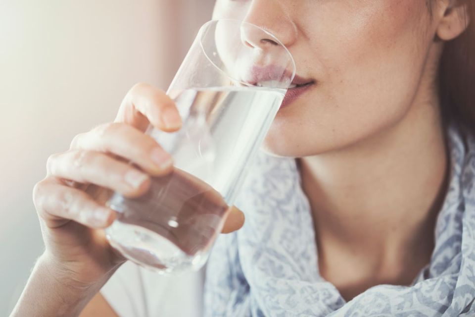 Frau trinkt Leitungswasser aus Glas